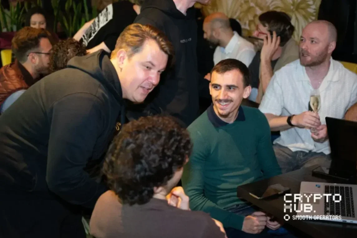 A group of people engaged in discussions at a technology event, with a focus on two men sharing a conversation.